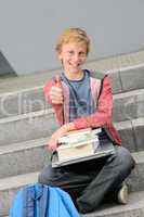 Successful student with books and laptop thumb-up