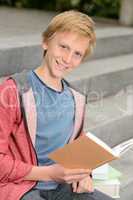 Happy teenage boy studying sitting on stairs