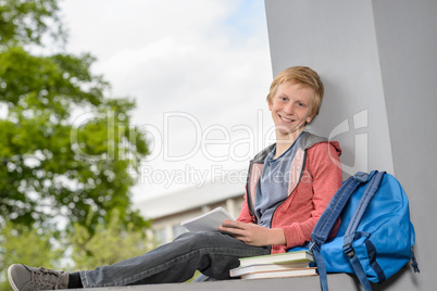 Happy boy studying sitting on wall campus