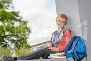 Happy boy studying sitting on wall campus