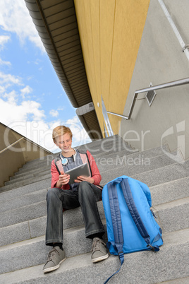 Student boy using tablet sitting on steps