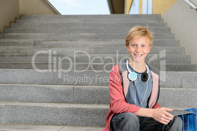 Happy student with tablet sitting on steps