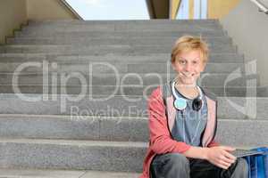 Happy student with tablet sitting on steps