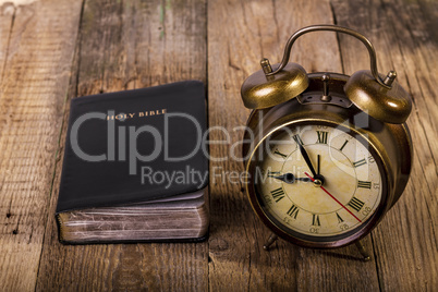 Bible with clock on wood