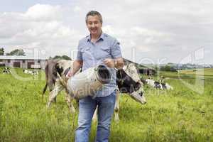 Farmer with milk churns in front of his cows