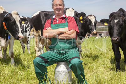 Farmer sitting on the milk jug in front of his cows