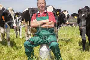Farmer sitting on the milk jug in front of his cows