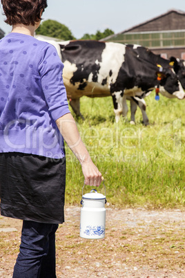 Woman with household milk jug in front of the cows