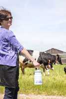 Woman with household milk jug in front of the cows