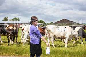 Woman with household milk jug in front of the cows