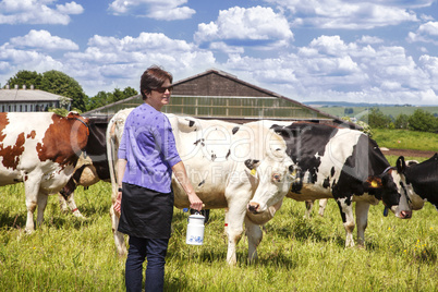 Woman with household milk jug in front of the cows