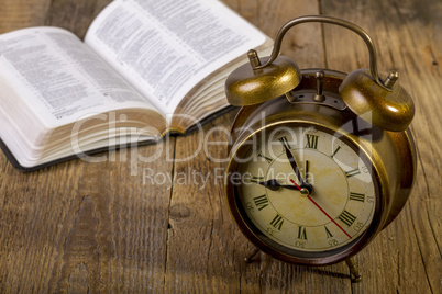 Bible with clock on wood