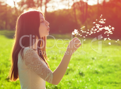 woman blowing on a dandelion