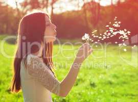 woman blowing on a dandelion