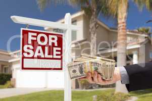 Buyer Handing Over Cash for House with For Sale Sign