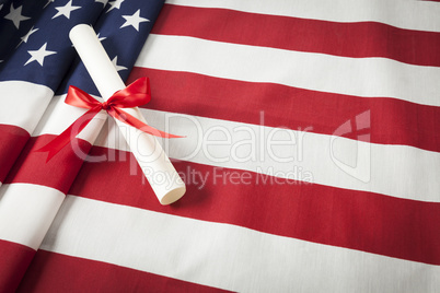 Ribbon Wrapped Diploma Resting on American Flag with Copy Space