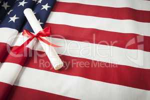 Ribbon Wrapped Diploma Resting on American Flag with Copy Space