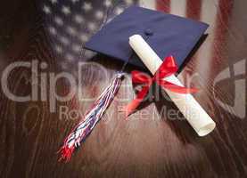 Graduation Cap and Dipoma on Table with American Flag Reflection