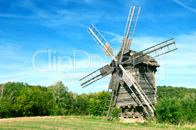 Old wooden windmill in the background of the autumn forest