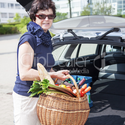 Woman lifts filled basket in the car