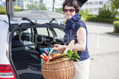 Woman lifts filled basket in the car