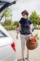 Woman lifts filled basket in the car
