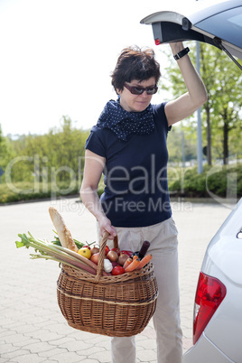 Woman lifts filled basket in the car