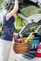 Woman lifts filled basket in the car