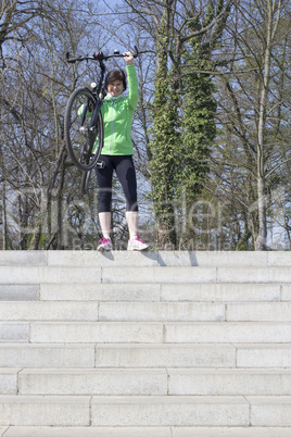 Bicyclist carries her bicycle over the stairs