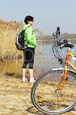 Woman standing with bicycle at the lake