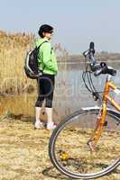 Woman standing with bicycle at the lake
