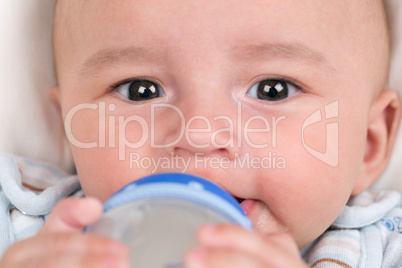 Baby trinkt Milch und hält die Flasche