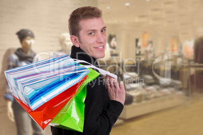 Lachender junger Mann beim Einkaufen mit Taschen in einem Gesch