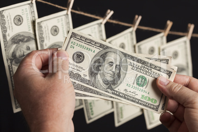 Male Holding Hundred Dollar Bills, Many Handing from Clothesline