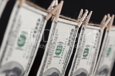 Hundred Dollar Bills Hanging From Clothesline on Dark Background