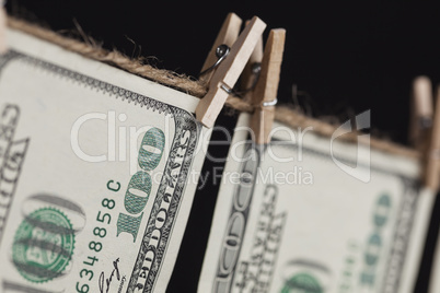 Hundred Dollar Bills Hanging From Clothesline on Dark Background