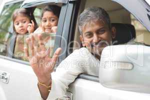 indian family waving hands in car
