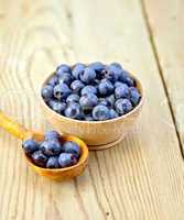 Blueberries in wooden bowl and spoon on board