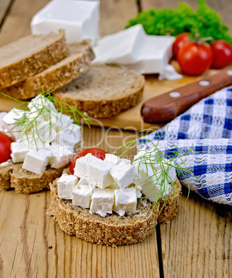 Bread with feta and tomatoes on board with knife