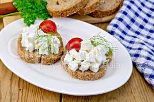 Bread with feta and tomatoes on plate on board