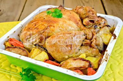 Chicken baked with vegetables in tray on board