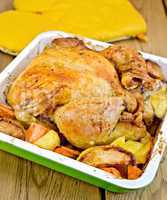 Chicken baked with vegetables on board and potholders
