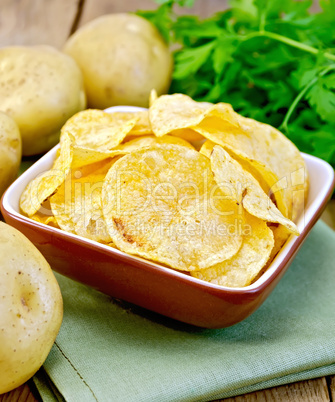 Chips in bowl with potato on napkin and board