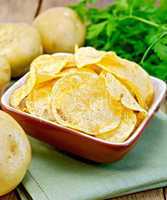 Chips in bowl with potato on napkin and board
