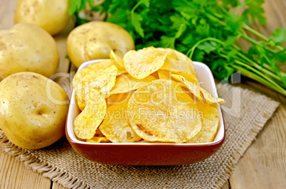 Chips in bowl with potatoes on sacking and board