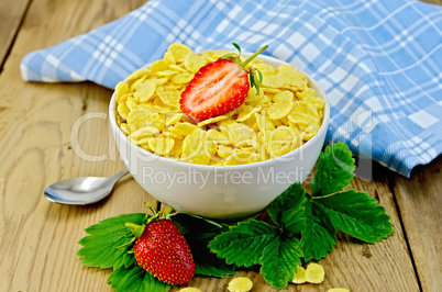 Cornflakes in white bowl with strawberries on board