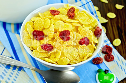 Cornflakes with dried cherries and milk on board