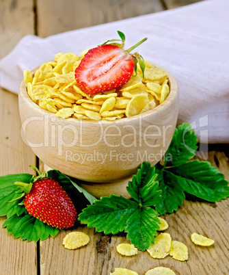 Cornflakes in wooden bowl with strawberries on board