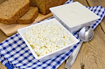 Curd and sour cream in bowls on board with bread