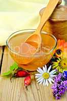 Honey with flowers and spoon on board